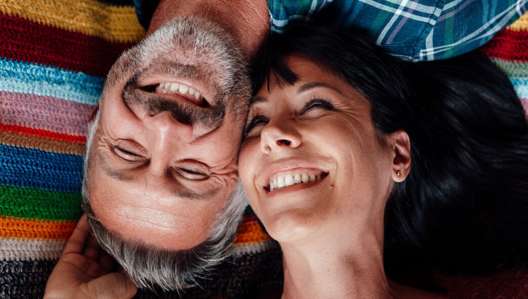 Two singles over 50 lie head to head on the floor and smile happily